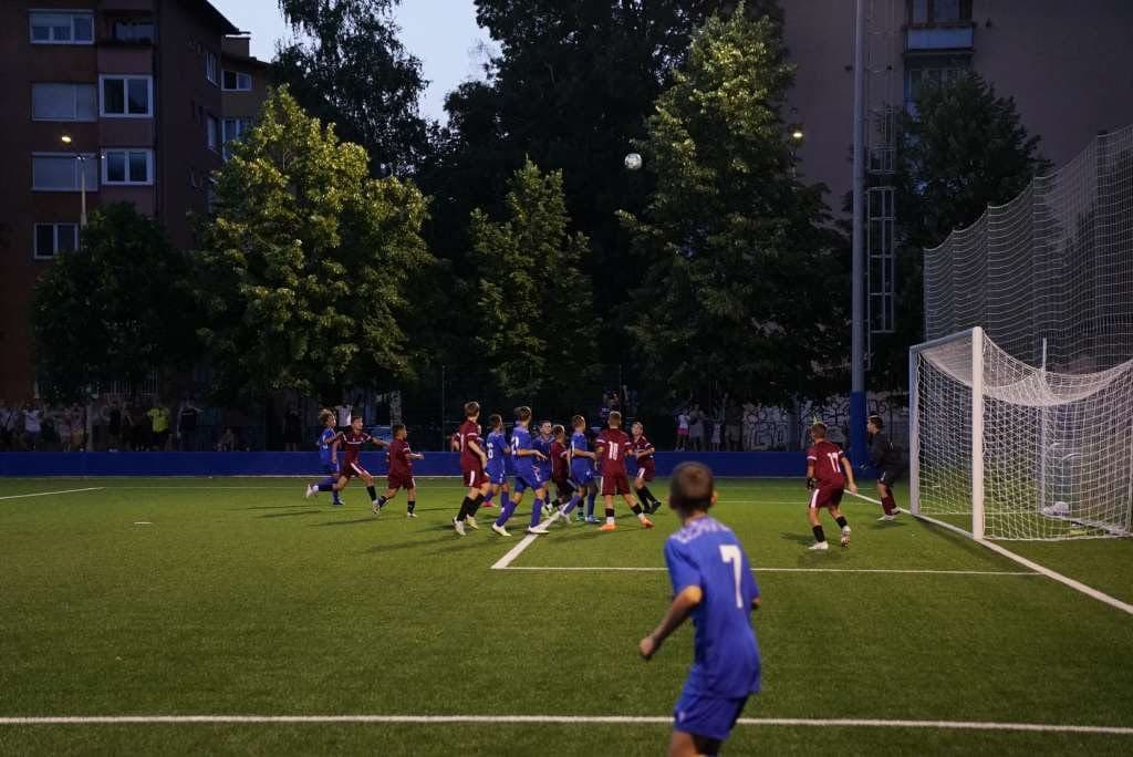 Youth footballers competing under floodlights at a HighFive camp in Bosnia